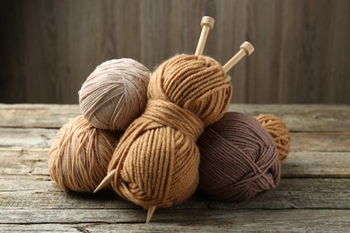 Photo of Skeins of soft yarn and knitting needles on wooden table