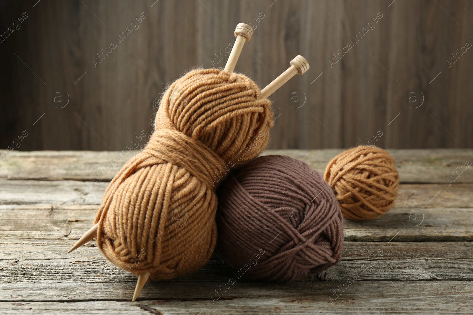 Photo of Skeins of soft yarn and knitting needles on wooden table