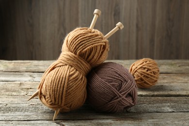 Photo of Skeins of soft yarn and knitting needles on wooden table