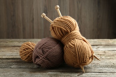 Photo of Skeins of soft yarn and knitting needles on wooden table