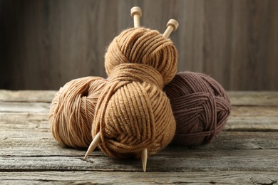 Skeins of soft yarn and knitting needles on wooden table