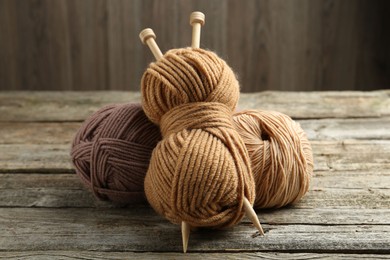 Skeins of soft yarn and knitting needles on wooden table