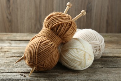 Skeins of soft yarn and knitting needles on wooden table