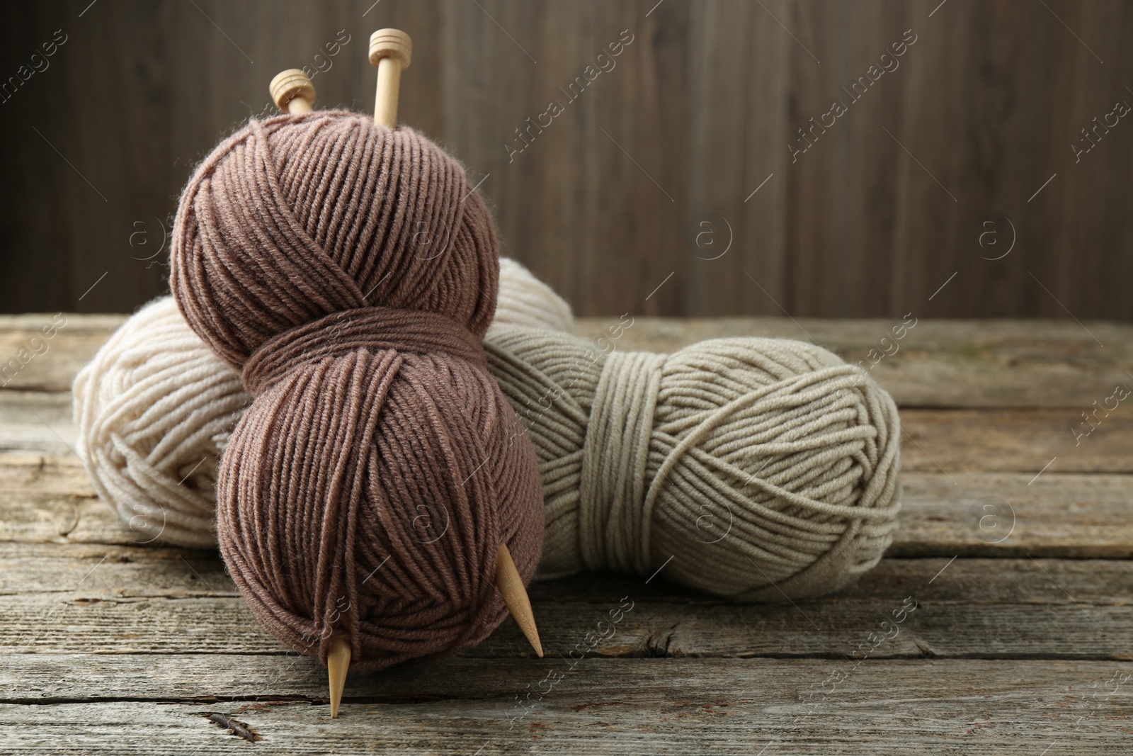 Photo of Skeins of soft yarn and knitting needles on wooden table