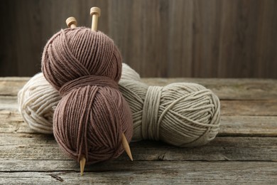 Skeins of soft yarn and knitting needles on wooden table