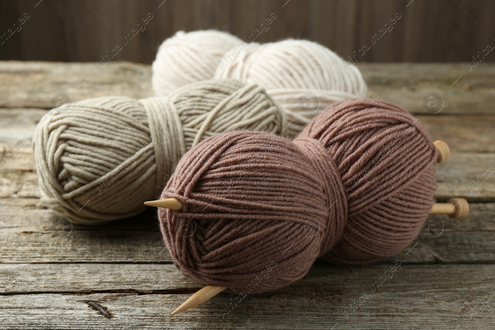 Photo of Skeins of soft yarn and knitting needles on wooden table