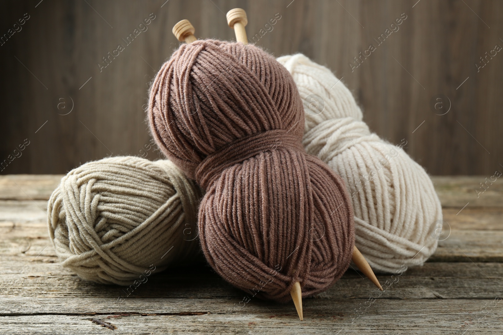 Photo of Skeins of soft yarn and knitting needles on wooden table