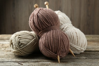 Skeins of soft yarn and knitting needles on wooden table