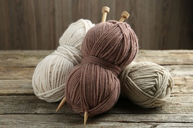 Skeins of soft yarn and knitting needles on wooden table