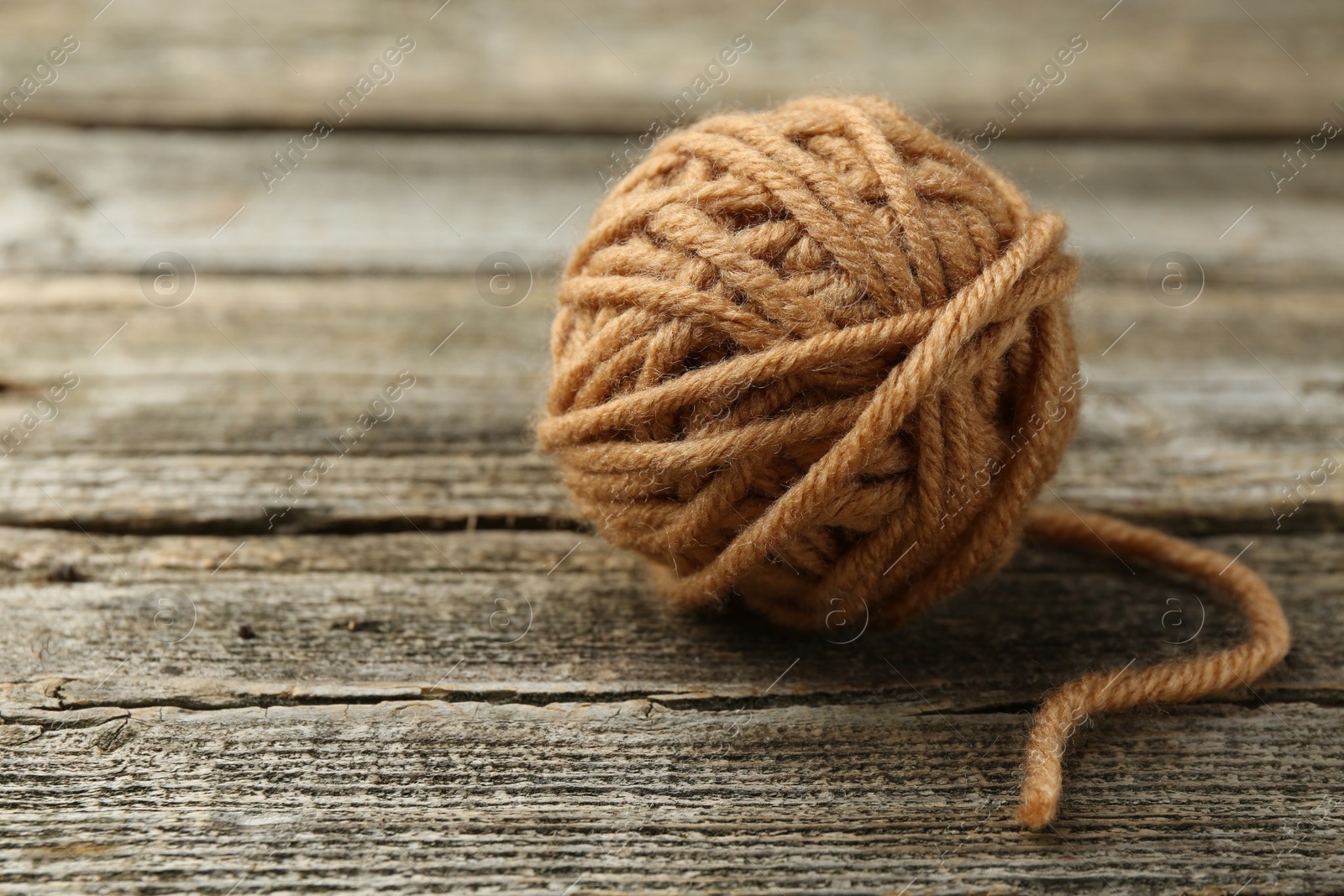 Photo of Skein of soft yarn for knitting on wooden table, closeup. Space for text