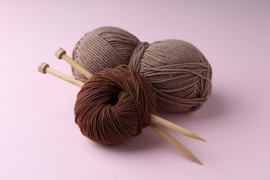 Photo of Skeins of yarn and knitting needles on pink background