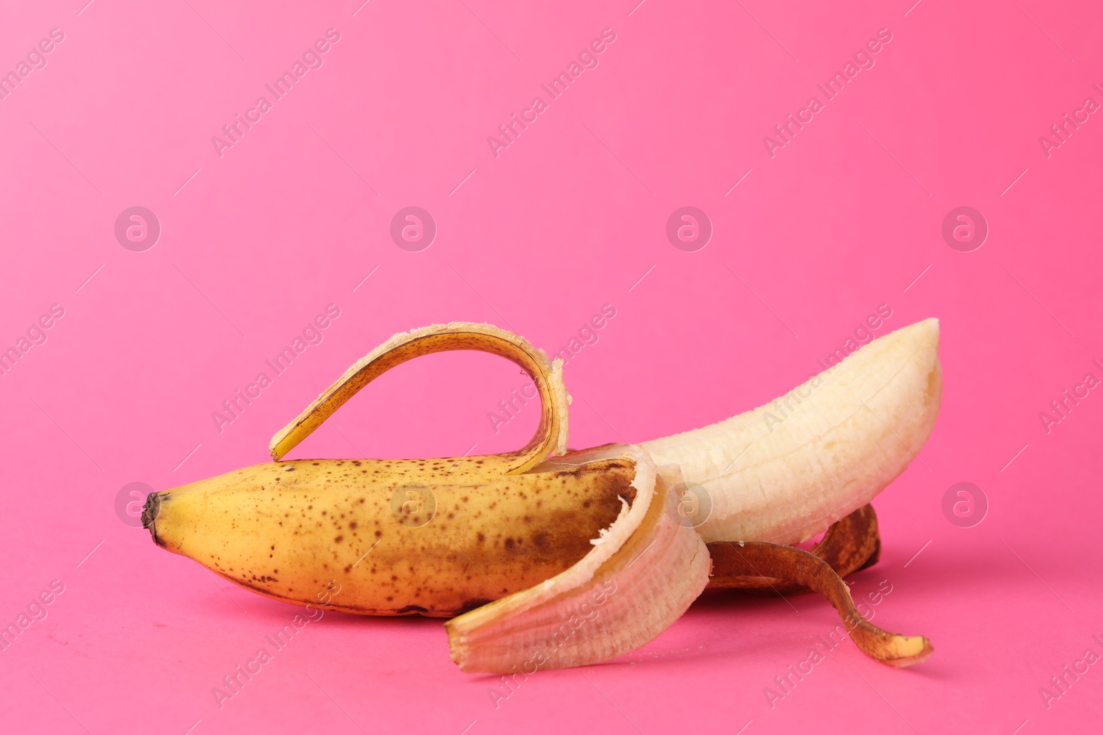 Photo of Ripe banana with dark spots on pink background