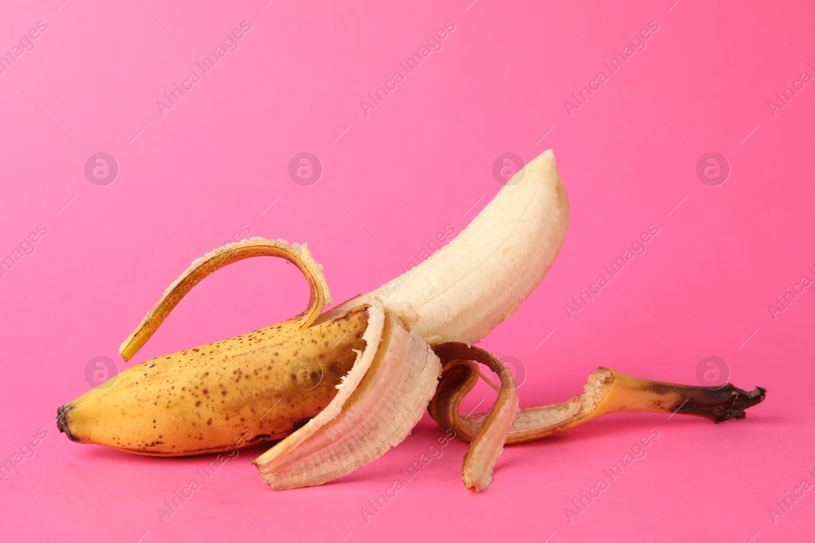 Photo of Ripe banana with dark spots on pink background