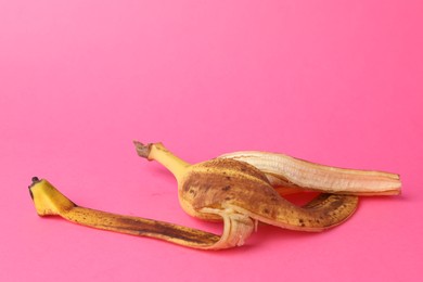 Photo of Banana peel with dark spots on pink background. Space for text