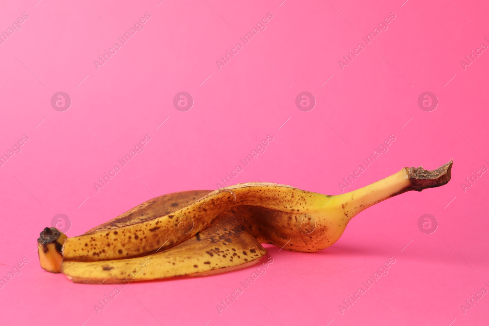 Photo of Banana peel with dark spots on pink background. Space for text