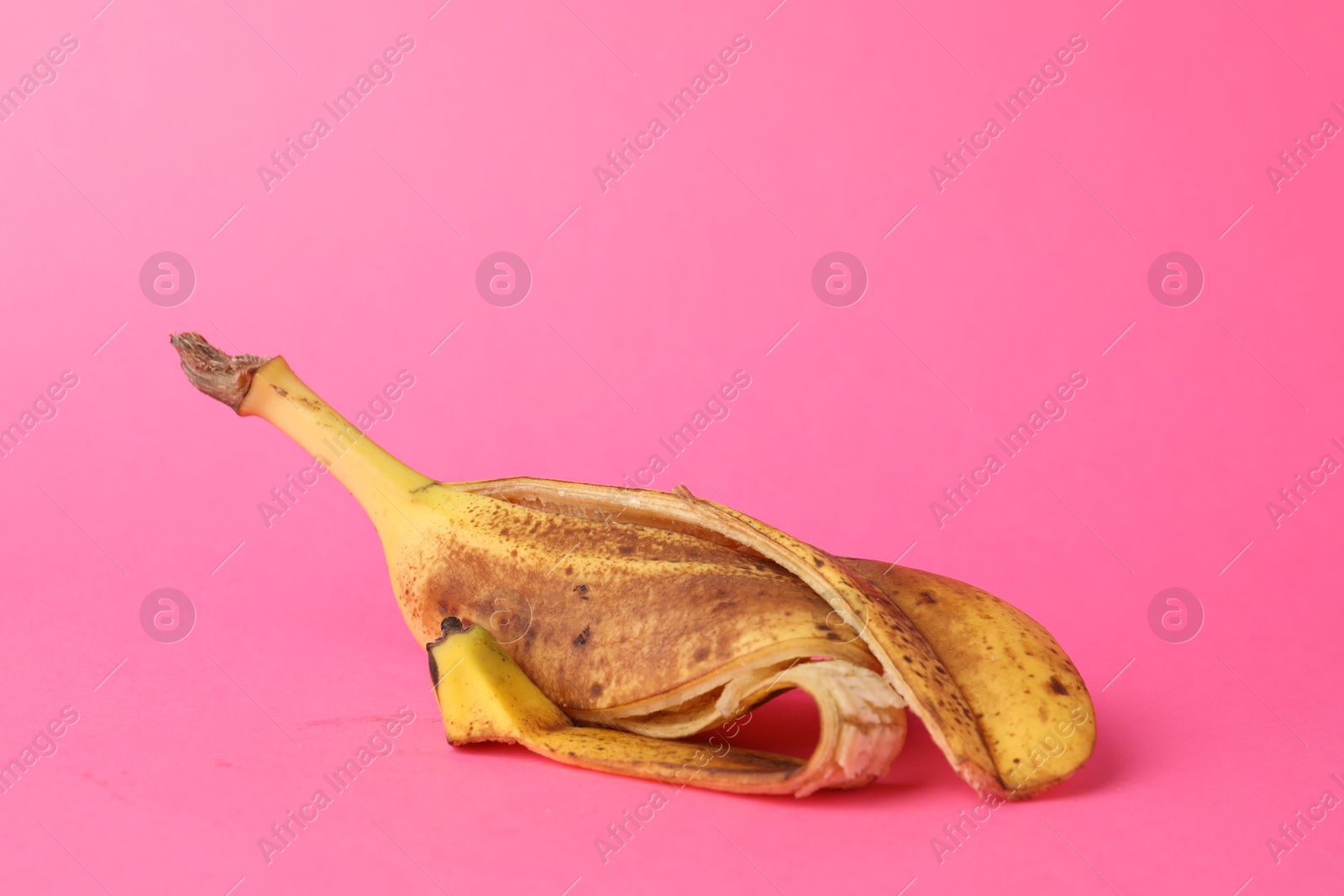 Photo of Banana peel with dark spots on pink background. Space for text