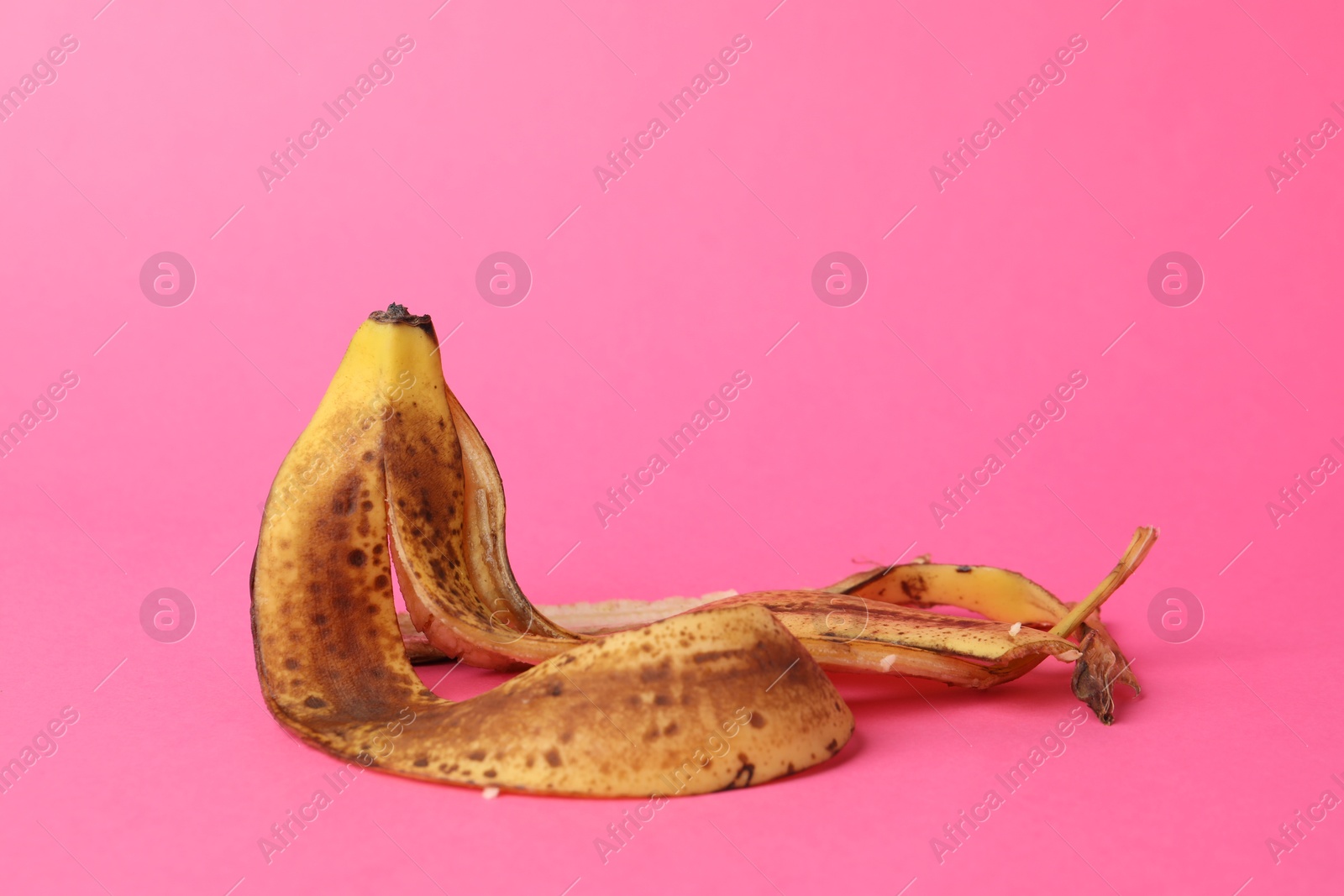 Photo of Banana peel with dark spots on pink background. Space for text