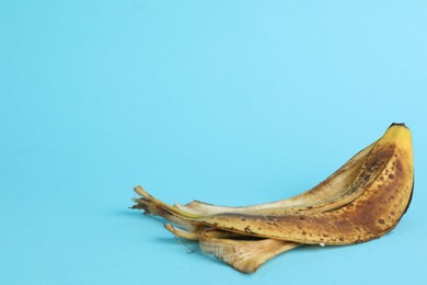 Photo of Banana peel with dark spots on light blue background. Space for text