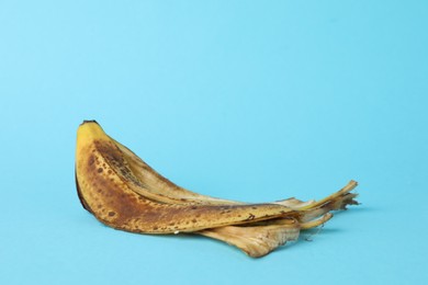 Photo of Banana peel with dark spots on light blue background. Space for text