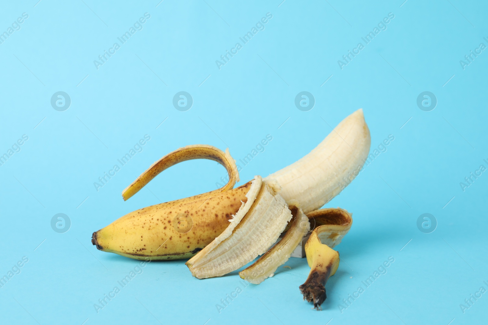 Photo of Ripe banana with dark spots on light blue background