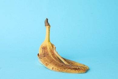 Photo of Banana peel with dark spots on light blue background