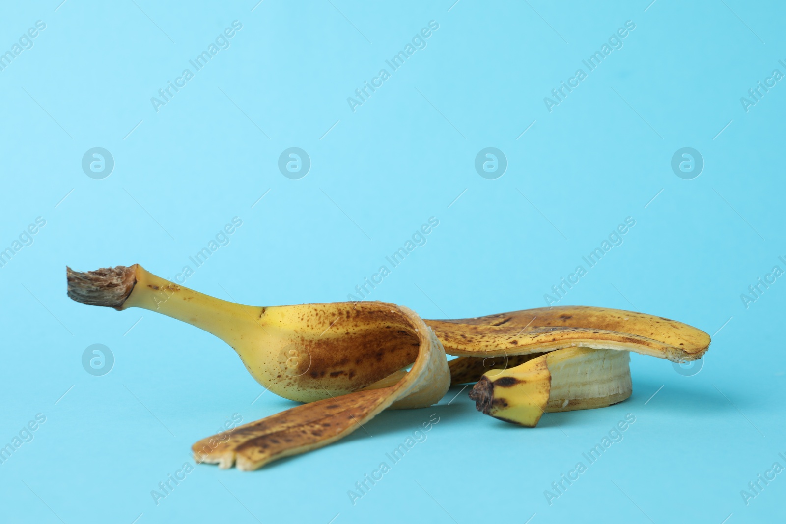 Photo of Banana peel with dark spots on light blue background