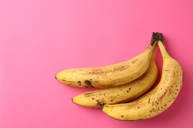 Photo of Bunch of ripe bananas with dark spots on pink background, top view