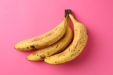 Photo of Bunch of ripe bananas with dark spots on pink background, top view