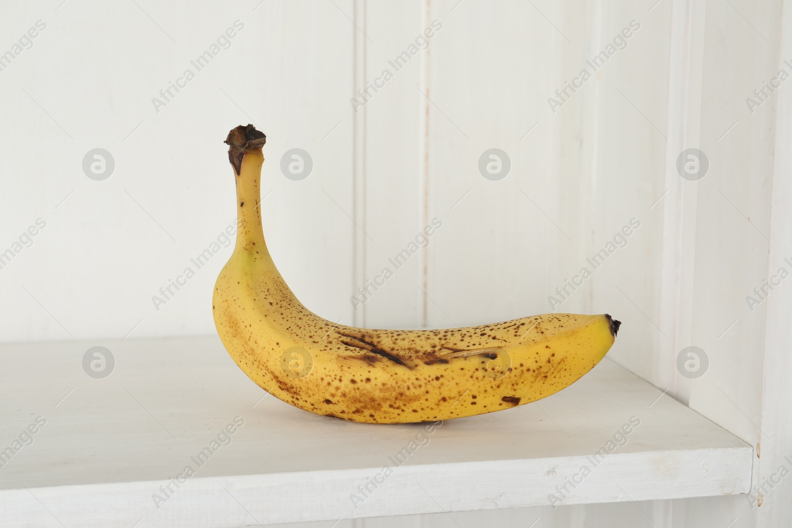 Photo of Ripe banana with dark spots on shelf