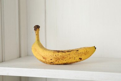 Photo of Ripe banana with dark spots on shelf