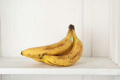 Bunch of ripe bananas with dark spots on shelf