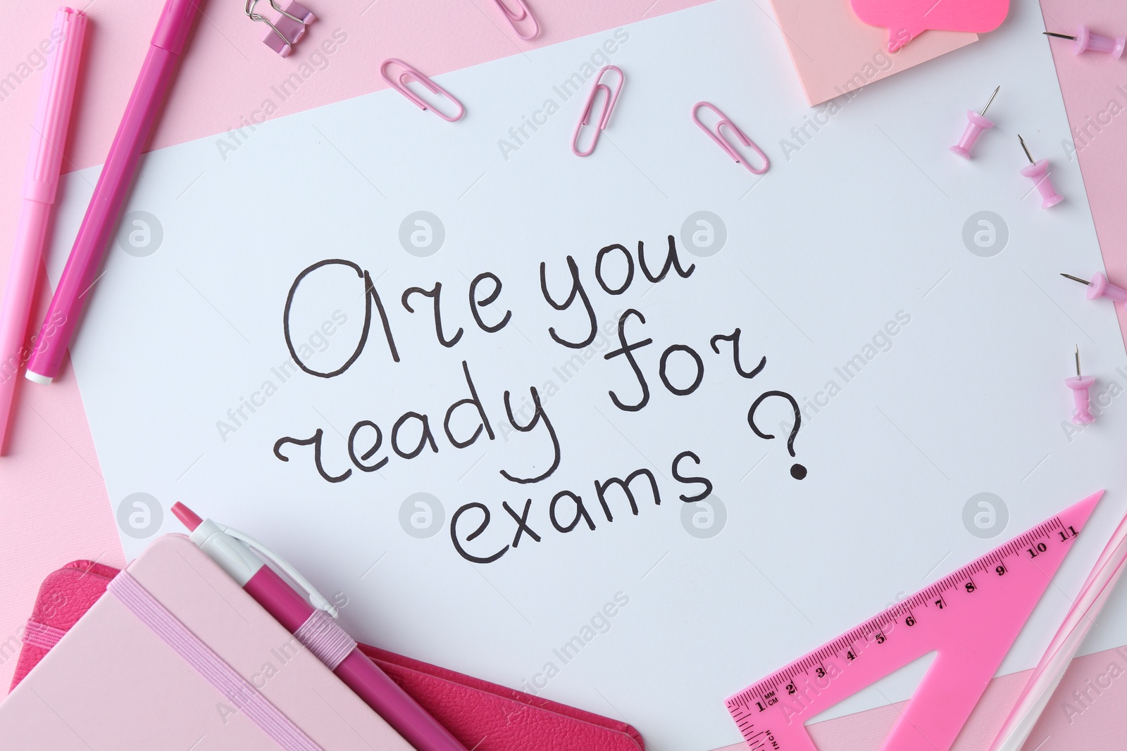 Photo of Paper note with question Are You Ready For Exams and stationery on pink background, flat lay