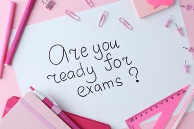 Paper note with question Are You Ready For Exams and stationery on pink background, flat lay