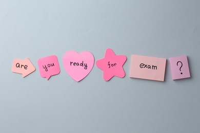 Photo of Sticky notes with question Are You Ready For Exam and stationery on grey background, flat lay