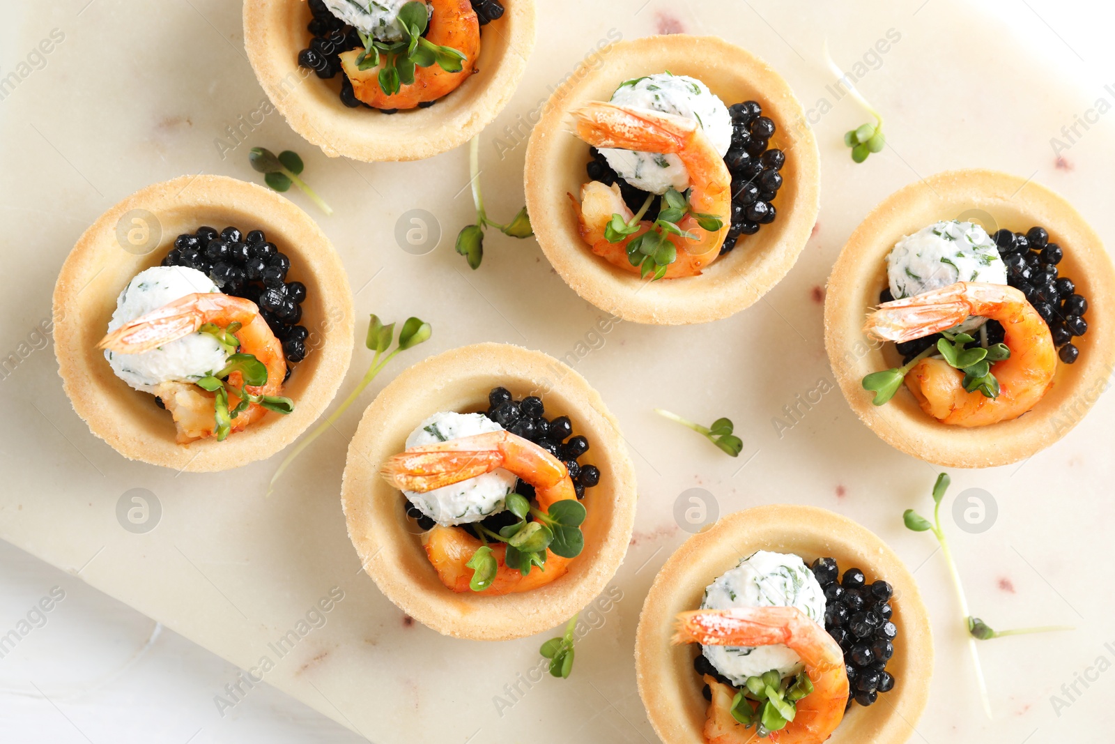 Photo of Delicious canapes with shrimps and black caviar on white table, top view