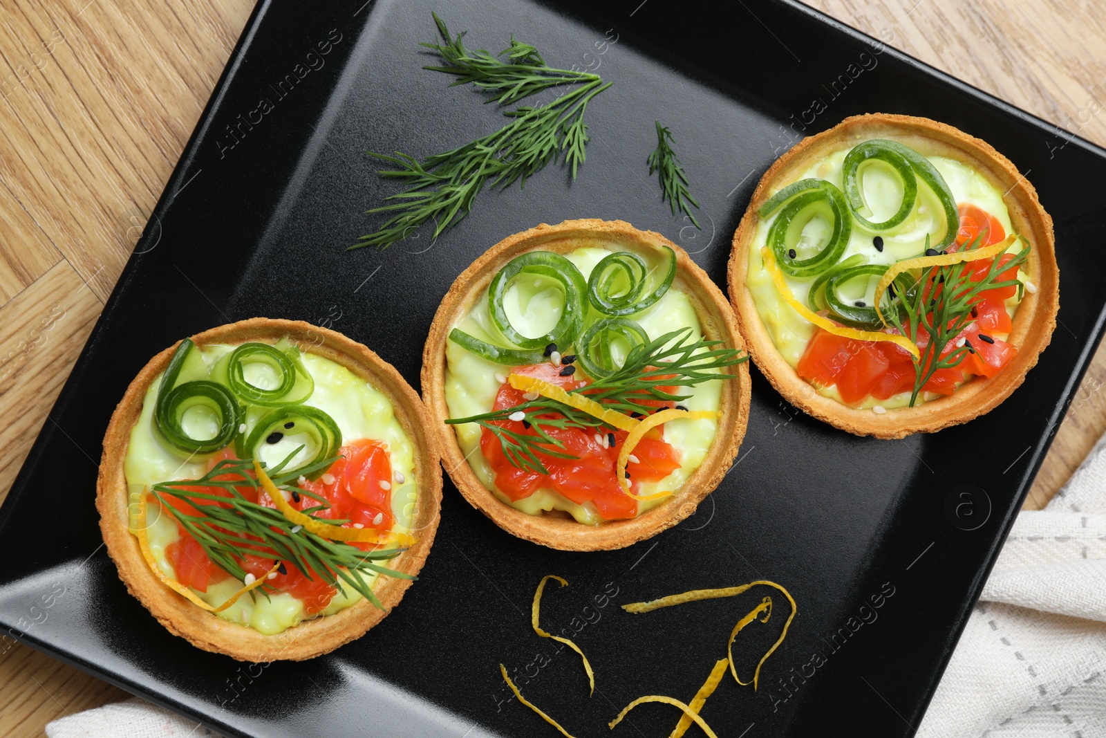 Photo of Delicious canapes with salmon on wooden table, top view