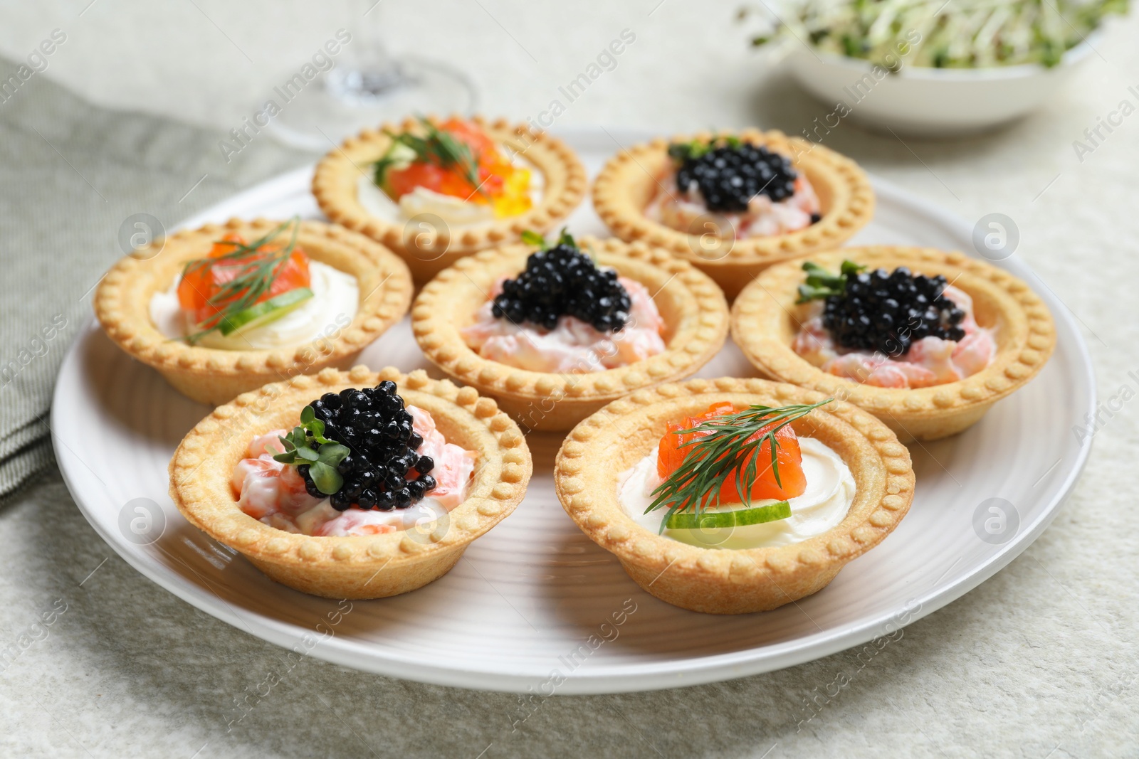 Photo of Delicious canapes with salmon and caviar on beige textured table, closeup