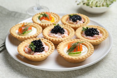 Photo of Delicious canapes with salmon and caviar on beige textured table, closeup