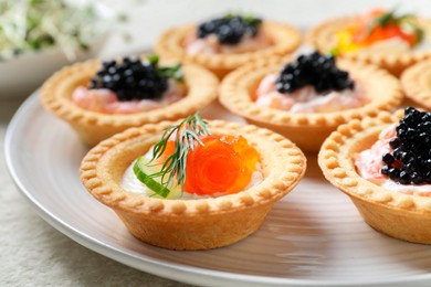 Delicious canapes with salmon and caviar on plate, closeup