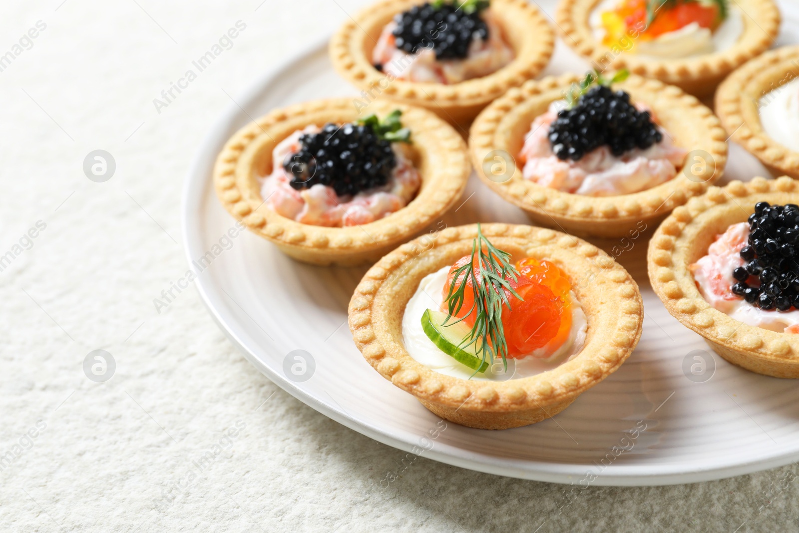 Photo of Delicious canapes with salmon and caviar on beige textured table, closeup