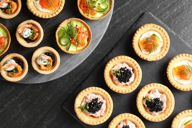 Photo of Delicious canapes with shrimps, salmon and caviar on black textured table, flat lay