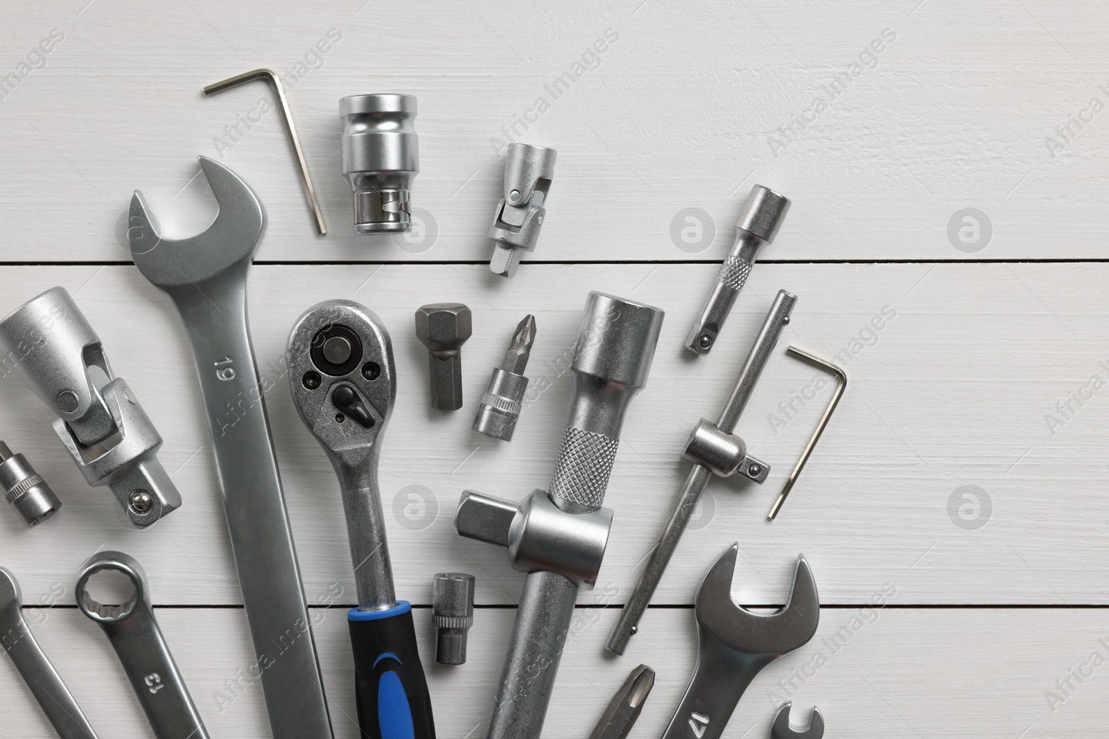 Photo of Auto mechanic's tools on white wooden table, flat lay