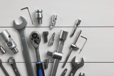 Auto mechanic's tools on white wooden table, flat lay