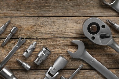 Photo of Different auto mechanic's tools on wooden table, flat lay. Space for text