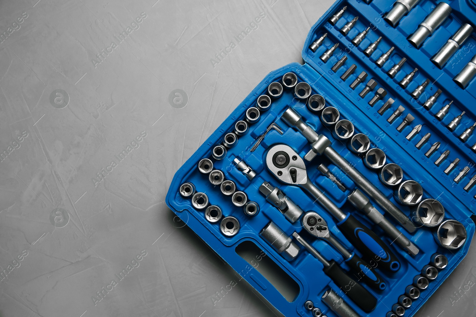 Photo of Different auto mechanic's tools in plastic box on grey table, top view. Space for text