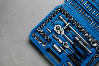 Photo of Different auto mechanic's tools in plastic box on grey table, top view. Space for text