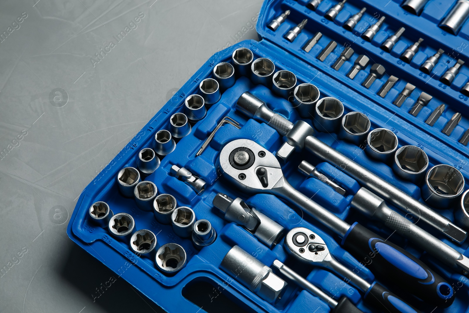 Photo of Different auto mechanic's tools in plastic box on grey table, above view