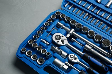 Different auto mechanic's tools in plastic box on grey table, above view