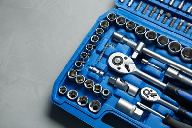 Photo of Different auto mechanic's tools in plastic box on grey table, above view. Space for text