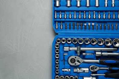 Photo of Different auto mechanic's tools in plastic box on grey table, top view. Space for text